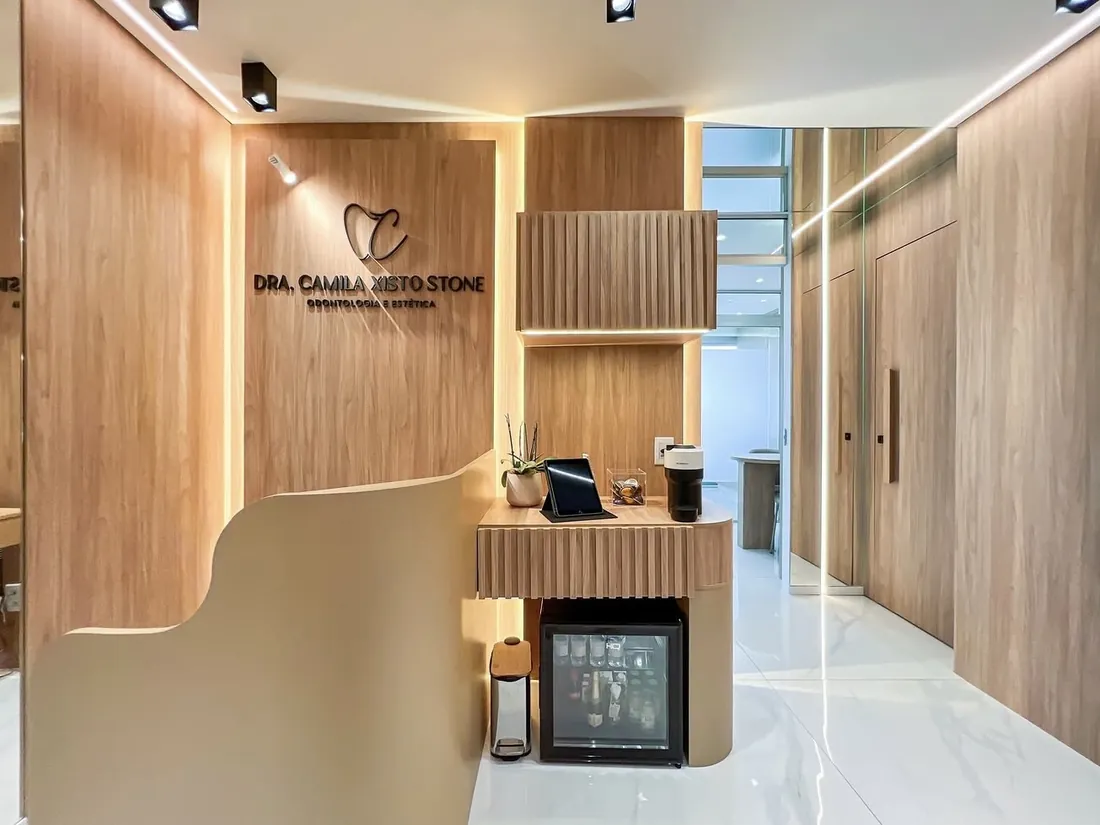 Recepção com a marca Dra. Camila Xisto Stone na parede
